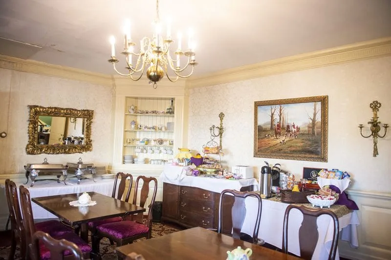 The dining room set for breakfast beneath a brass chandelier